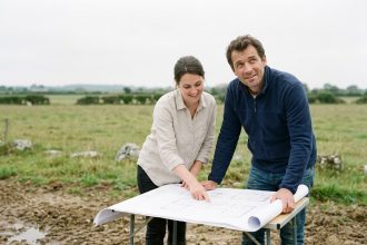 Couple étudiant les plans de leur future maison sur un terrain en Bretagne
