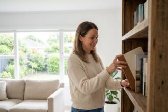 Jeune femme arrangeant des livres dans un salon lumineux